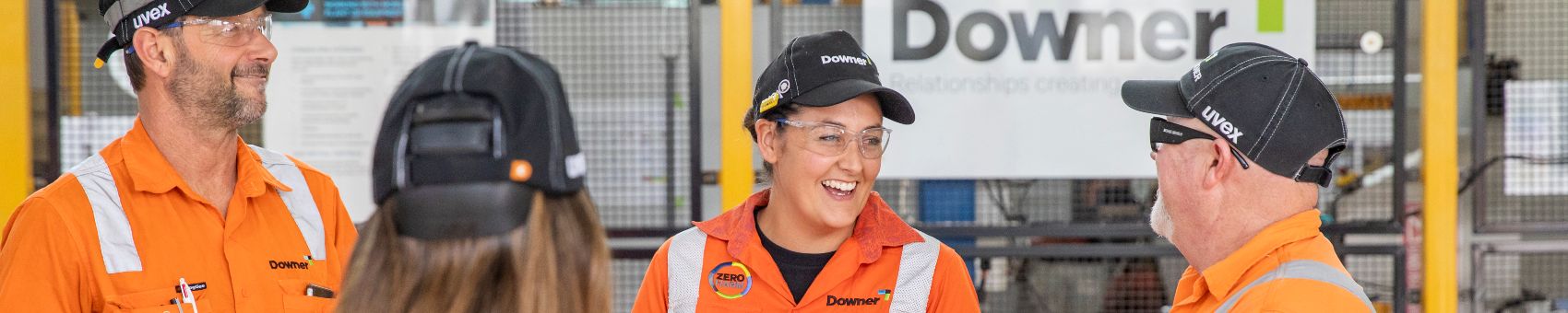 Life at Downer Four Downer employees in high vis stand together. They are laughing.